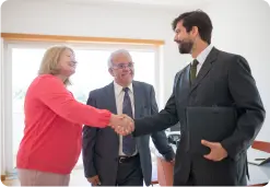 2 persons sealing an agreement by shaking hands in front of a witness